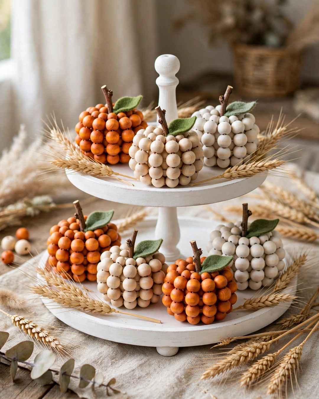 Handmade wood bead pumpkins in orange, cream, and white on a tiered tray