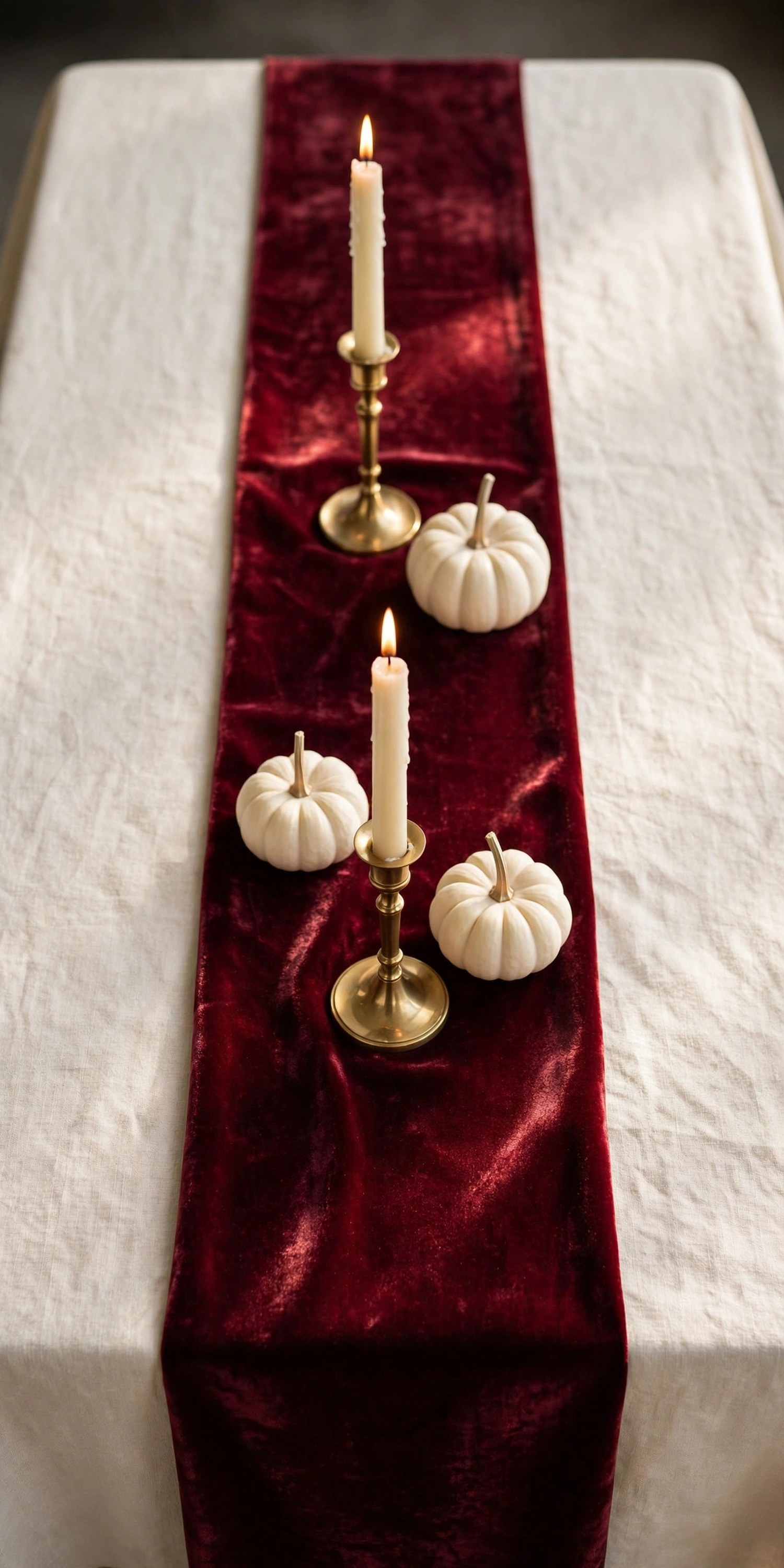 Burgundy velvet runner on a cream tablecloth with brass candles