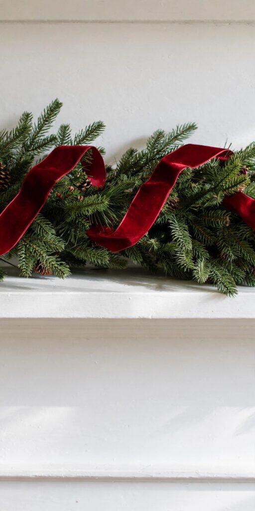 Deep-red velvet ribbon threaded through a pine mantel garland