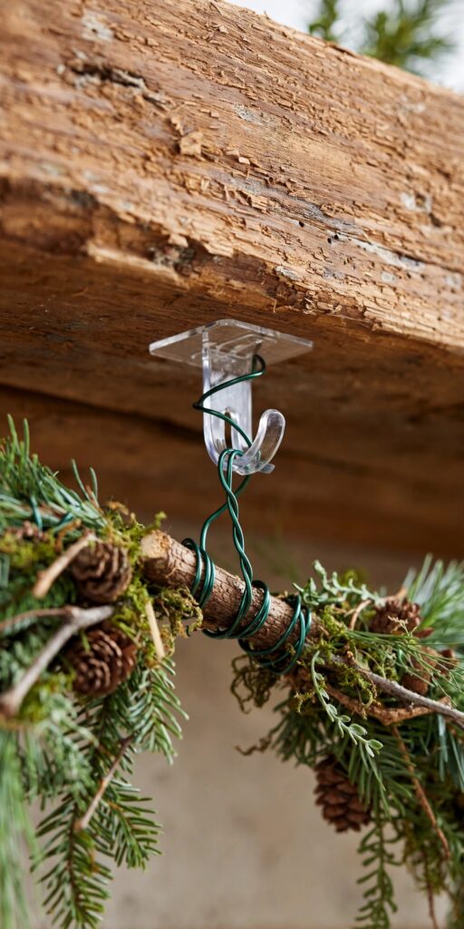 Clear removable hook and floral wire securing a garland under a mantel shelf